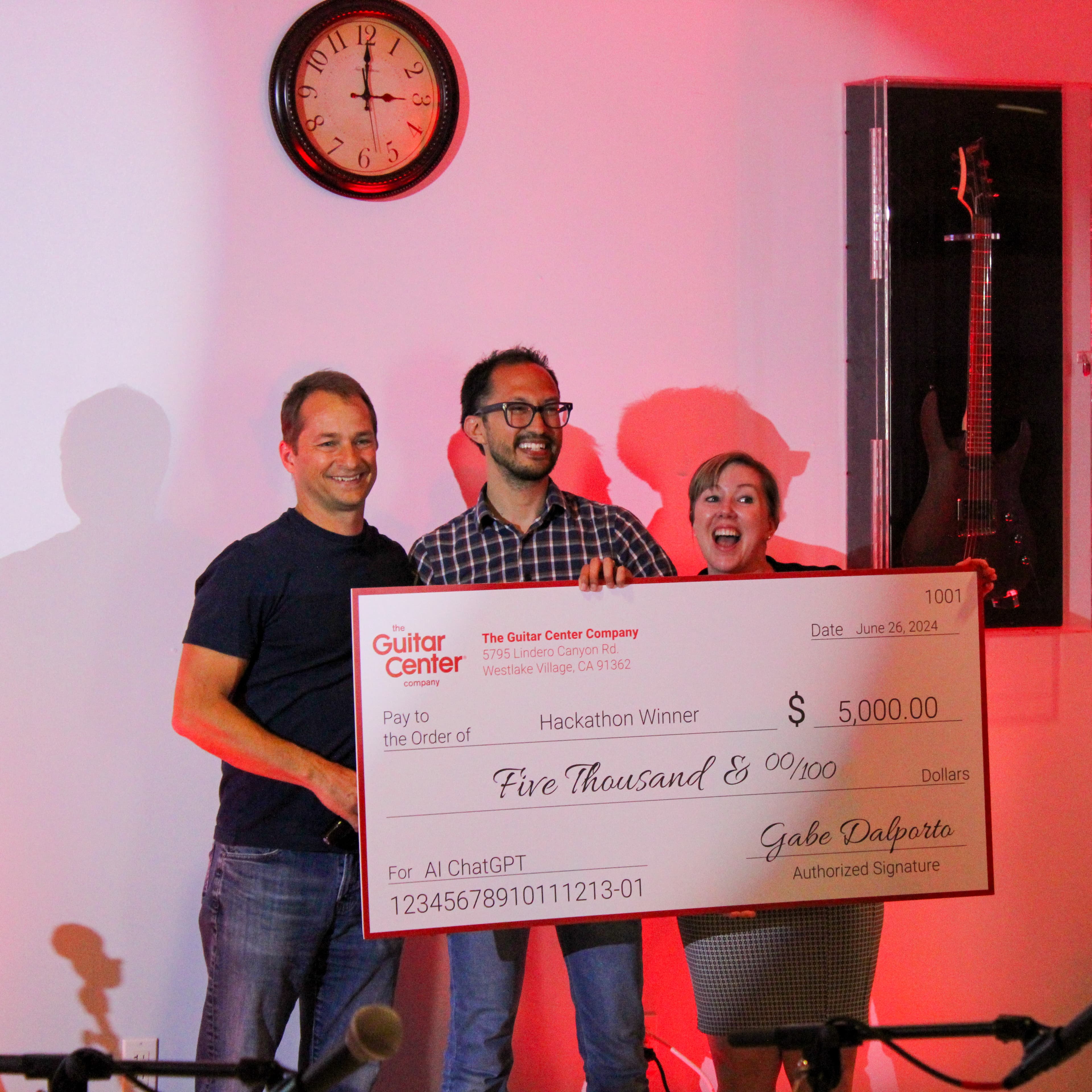 Hackathon photo showing Daniel Nash and teammates holding the winning check at Guitar Center's ChatGPT hackathon.